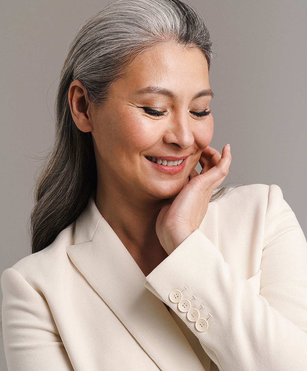 Smiling Lafayette facelift model with gray hair in a blazer.