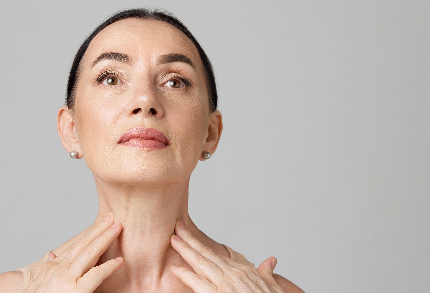 Lafayette facial plastic surgery model gently touching her neck, looking upwards.