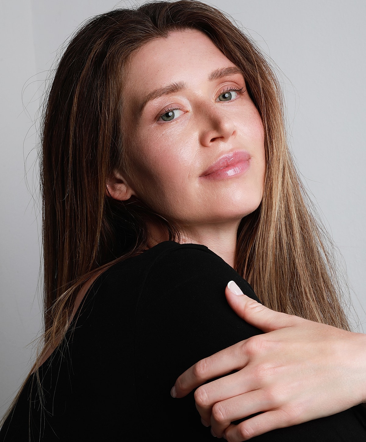 Lafayette chemical peel model with long hair posing thoughtfully against wall.