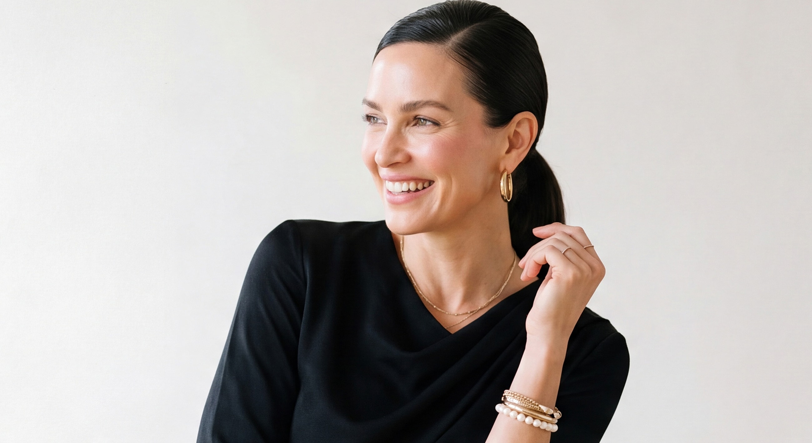 Smiling Lafayette buccal fat removal model wearing jewelry against neutral background